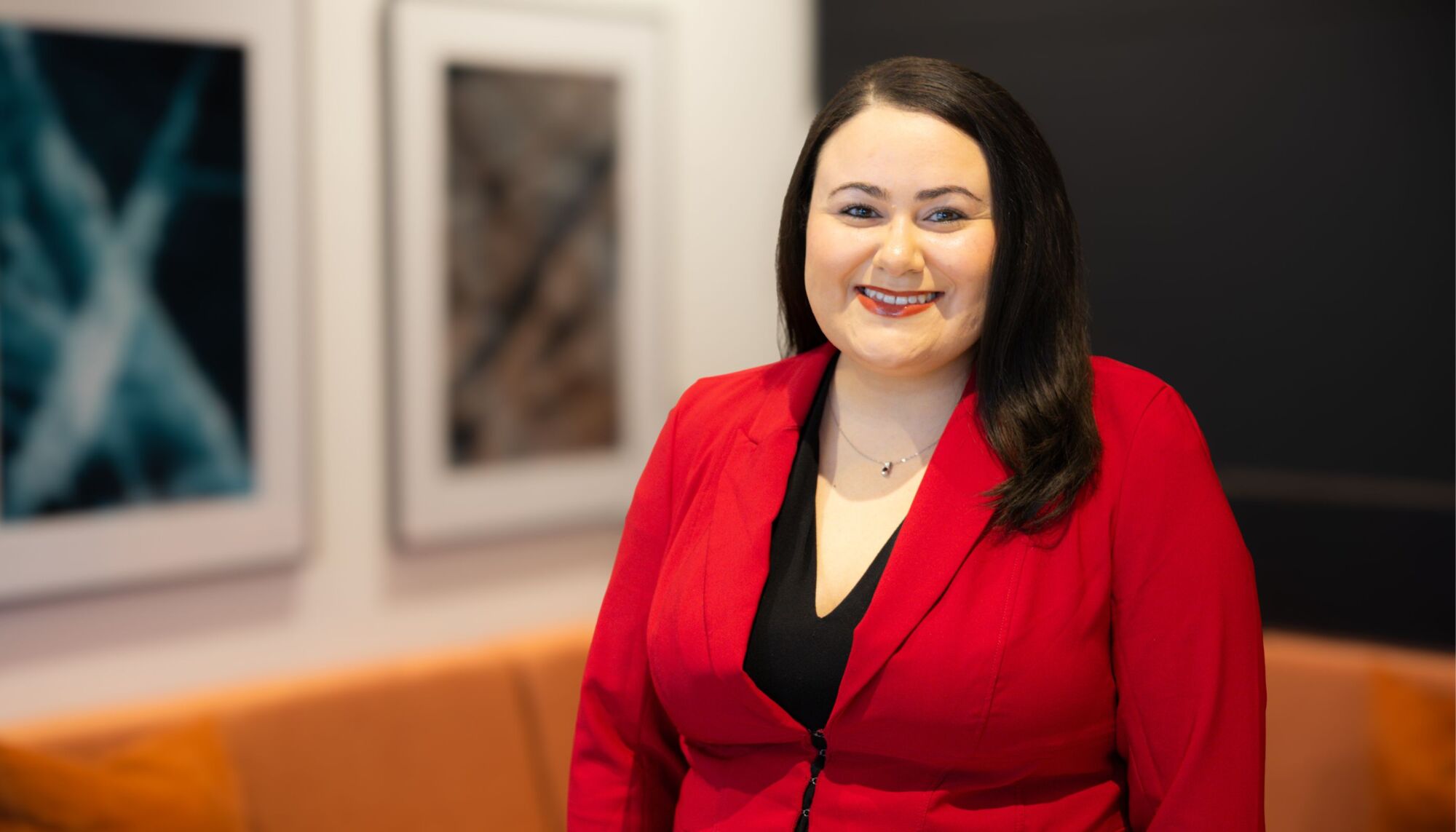 Woman smiling at camera wearing red blazer and black top