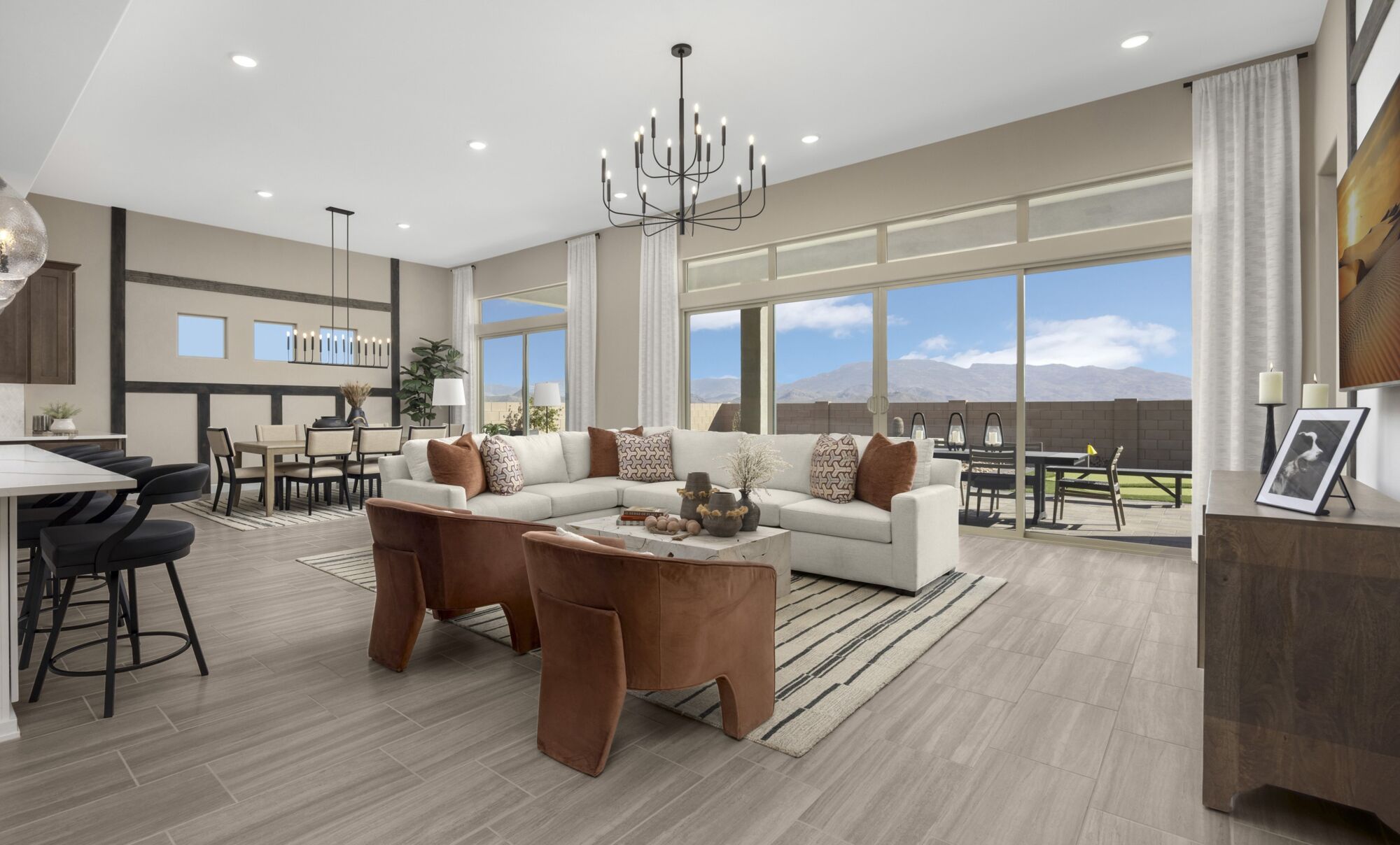 Greatroom with white couch, chairs, barstools, chandelier, dining table