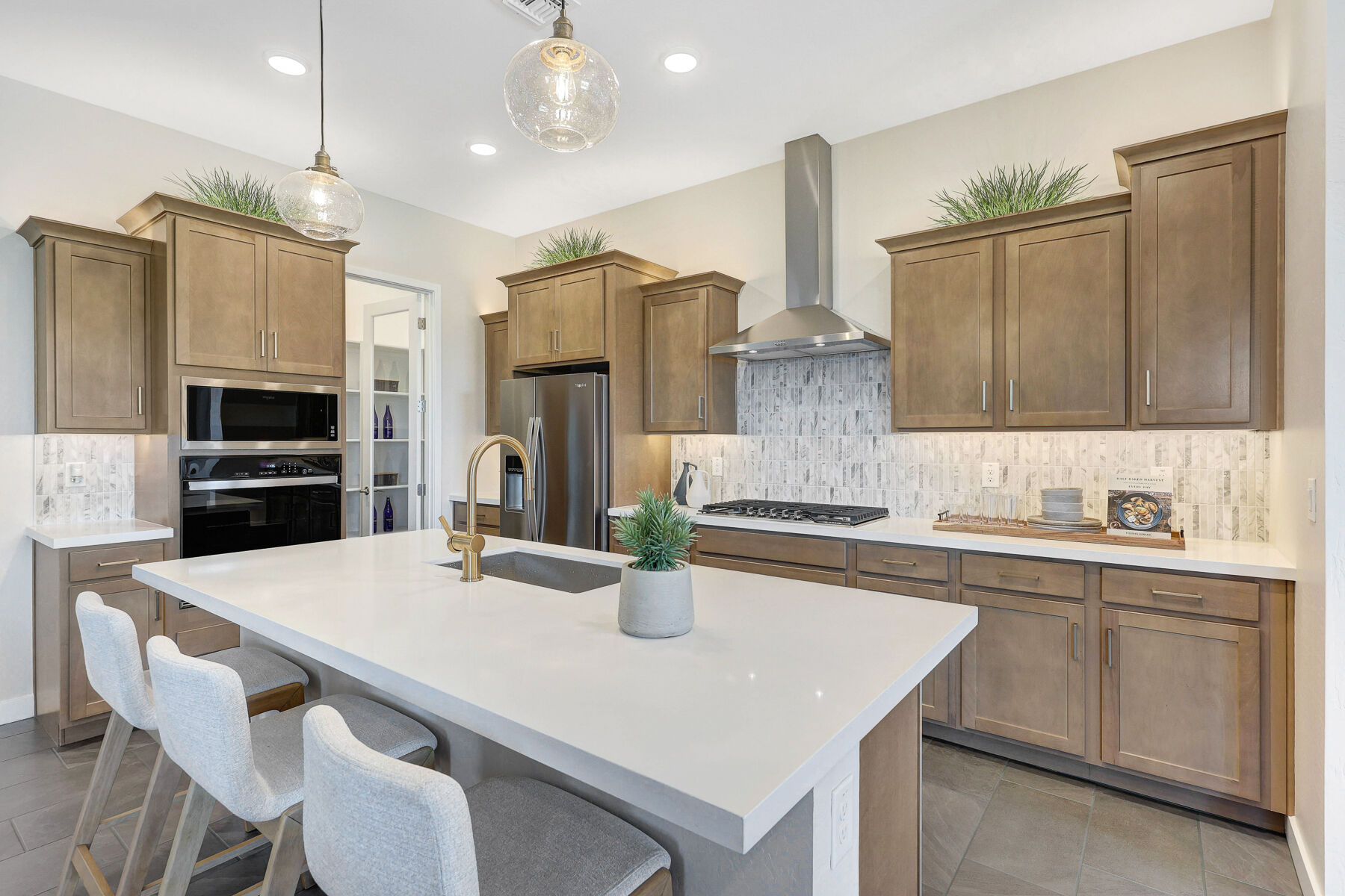 L-Shaped Kitchen with pendant light, light wood cabinets, cooktop, white cabinets, refrigerator, oven and tile flooring