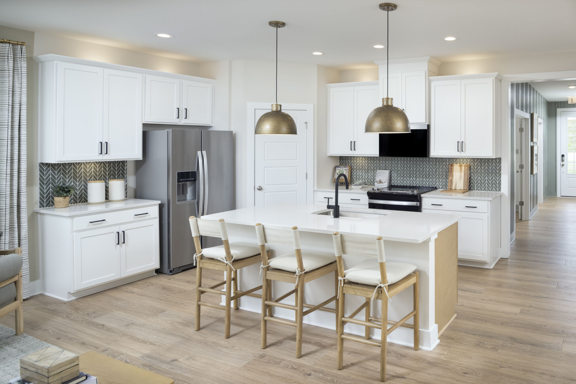 Kitchen with white cabinets and countertops, stainless steel appliances, and island breakfast bar.