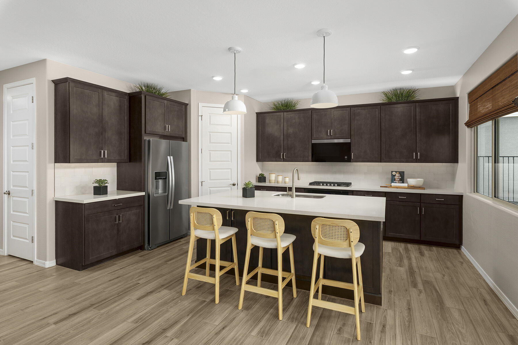 L-Shaped Kitchen with refrigerator, pendant light, door, dark wood cabinets, window and wood flooring