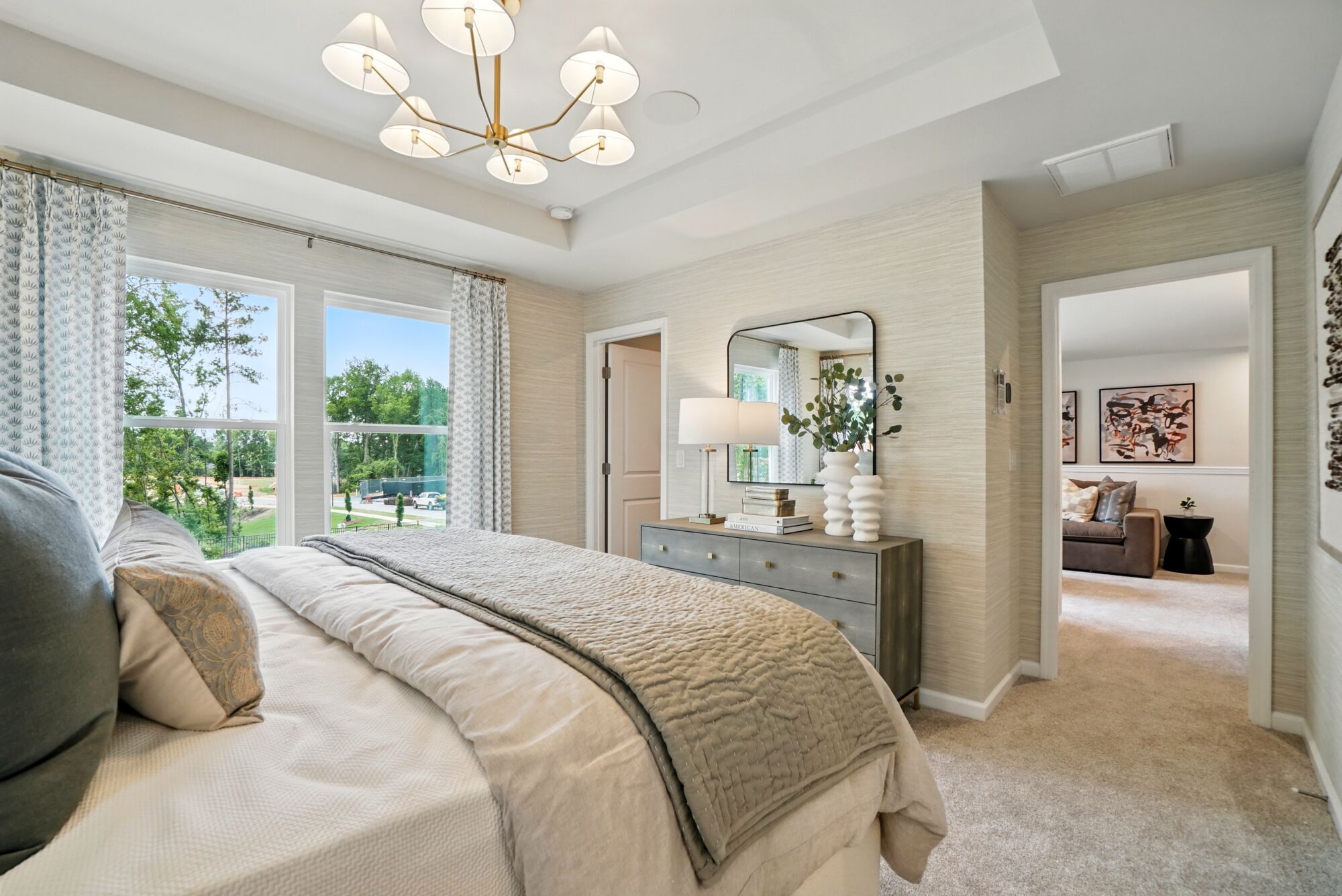 Owners Suite Bedroom with window, curtains, painting, mirror, door, carpet and pendant light