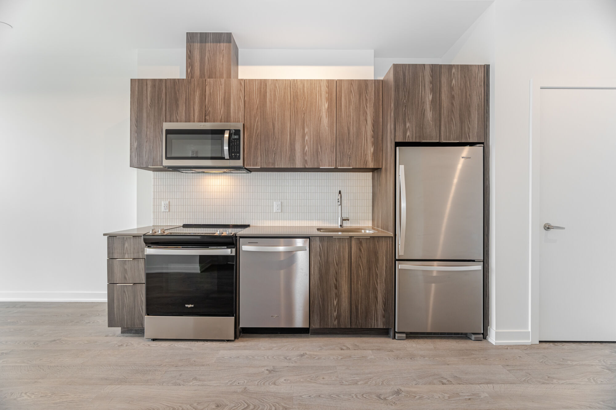 Kitchen with white cabinets, island, quartz countertop and stainless steel appliances