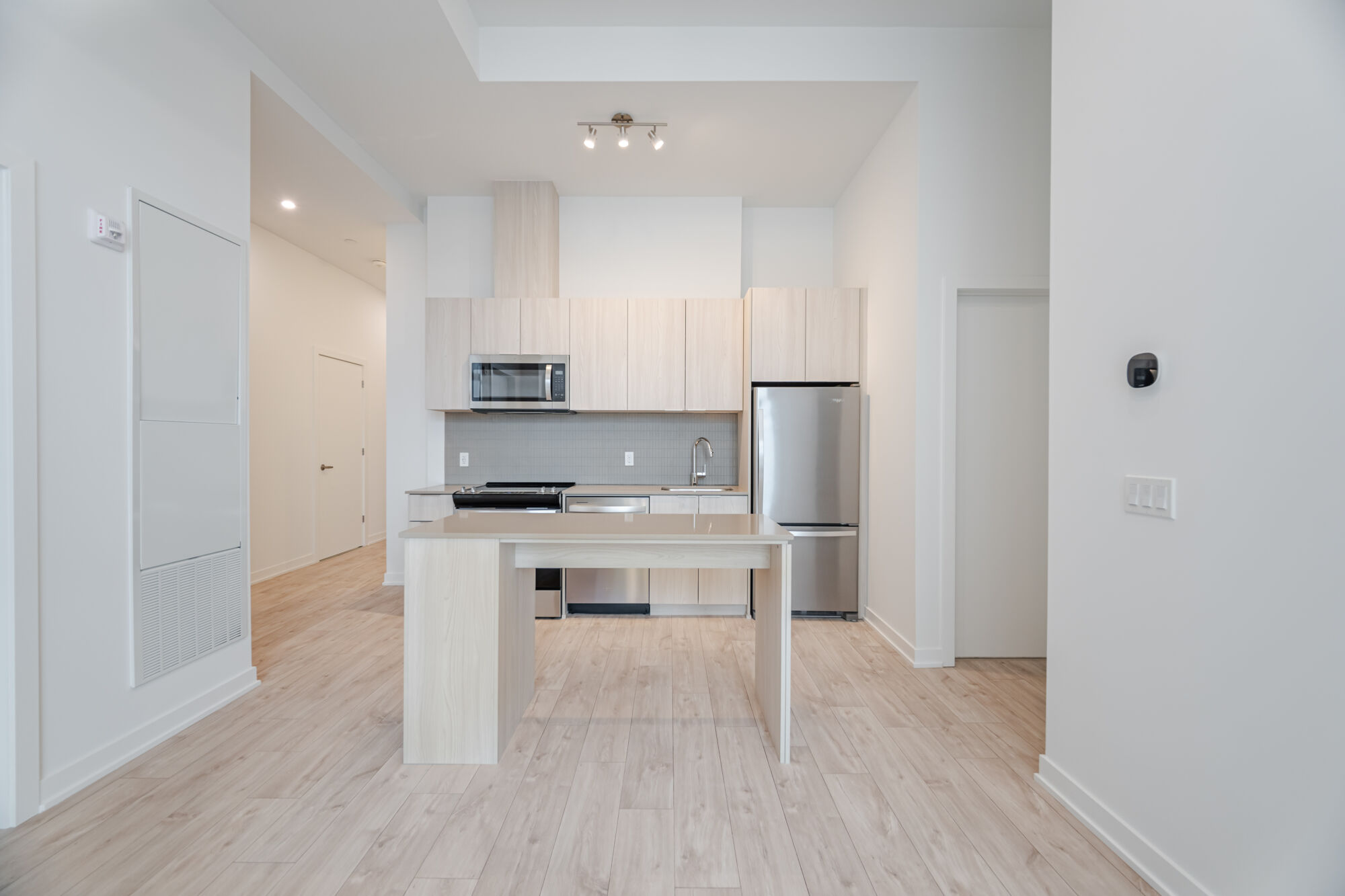 Condo Kitchen with white cabinetry, stainless steel appliances, kitchen island and quartz countertop. 