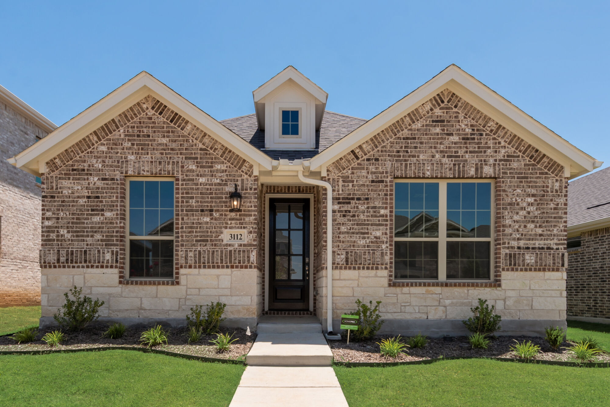 single story brick and stone house with steps up to front door with landscaping