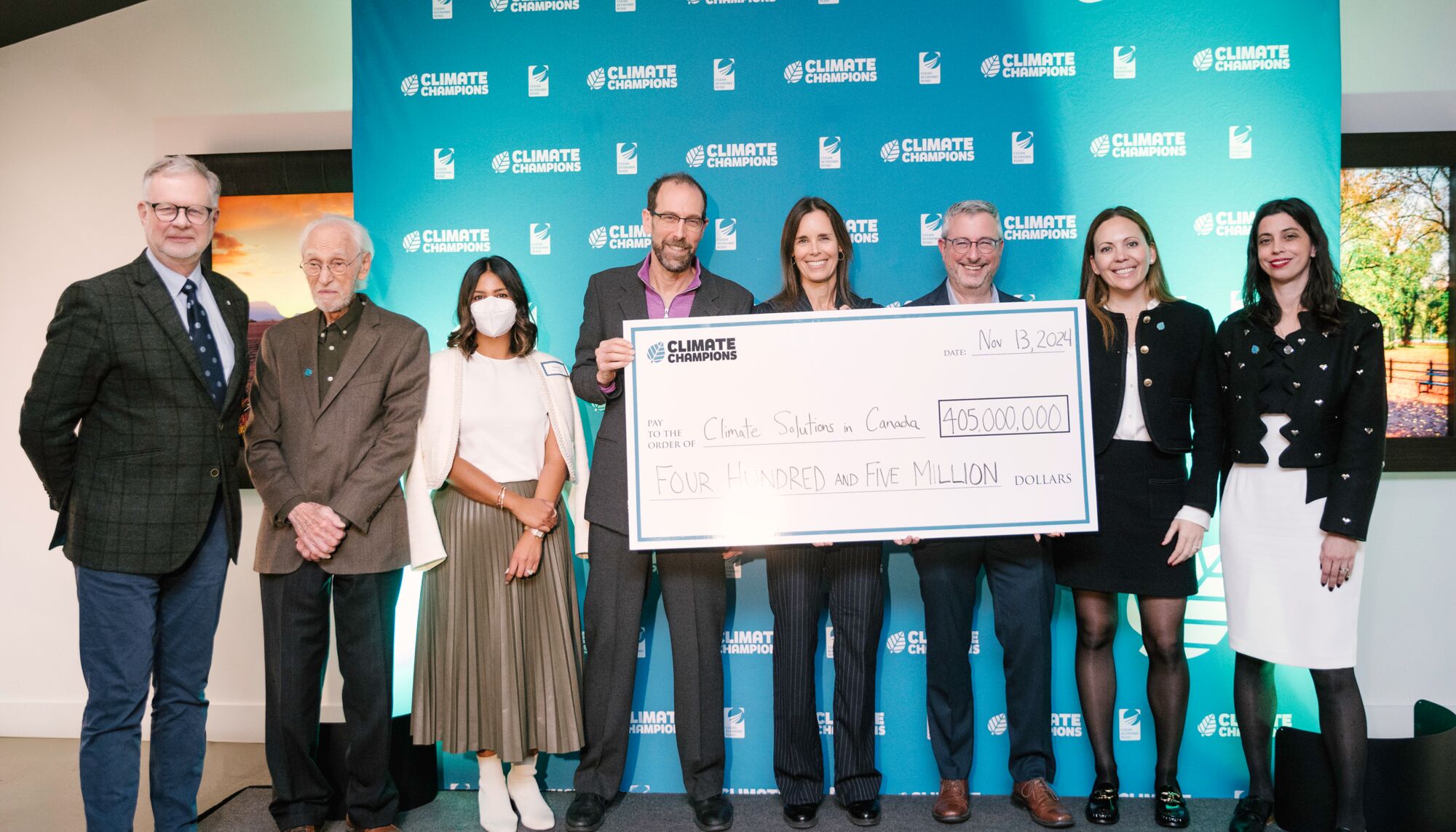 A group of people hold a cheque for four hundred and five million dollars