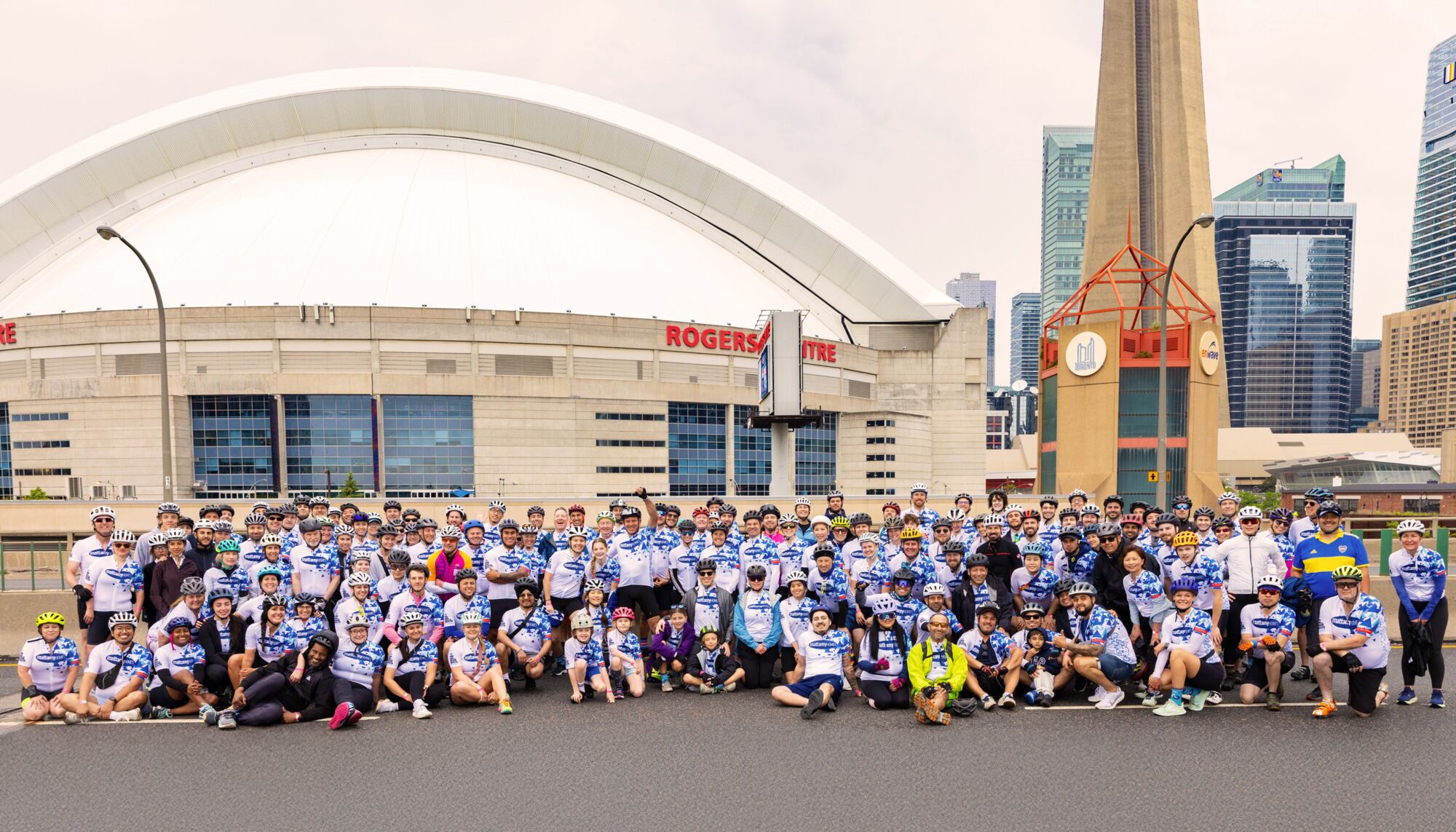 A large team wearing Mattamy Homes jerseys poses for a photo in front of the Rogers Centre and CN Tower