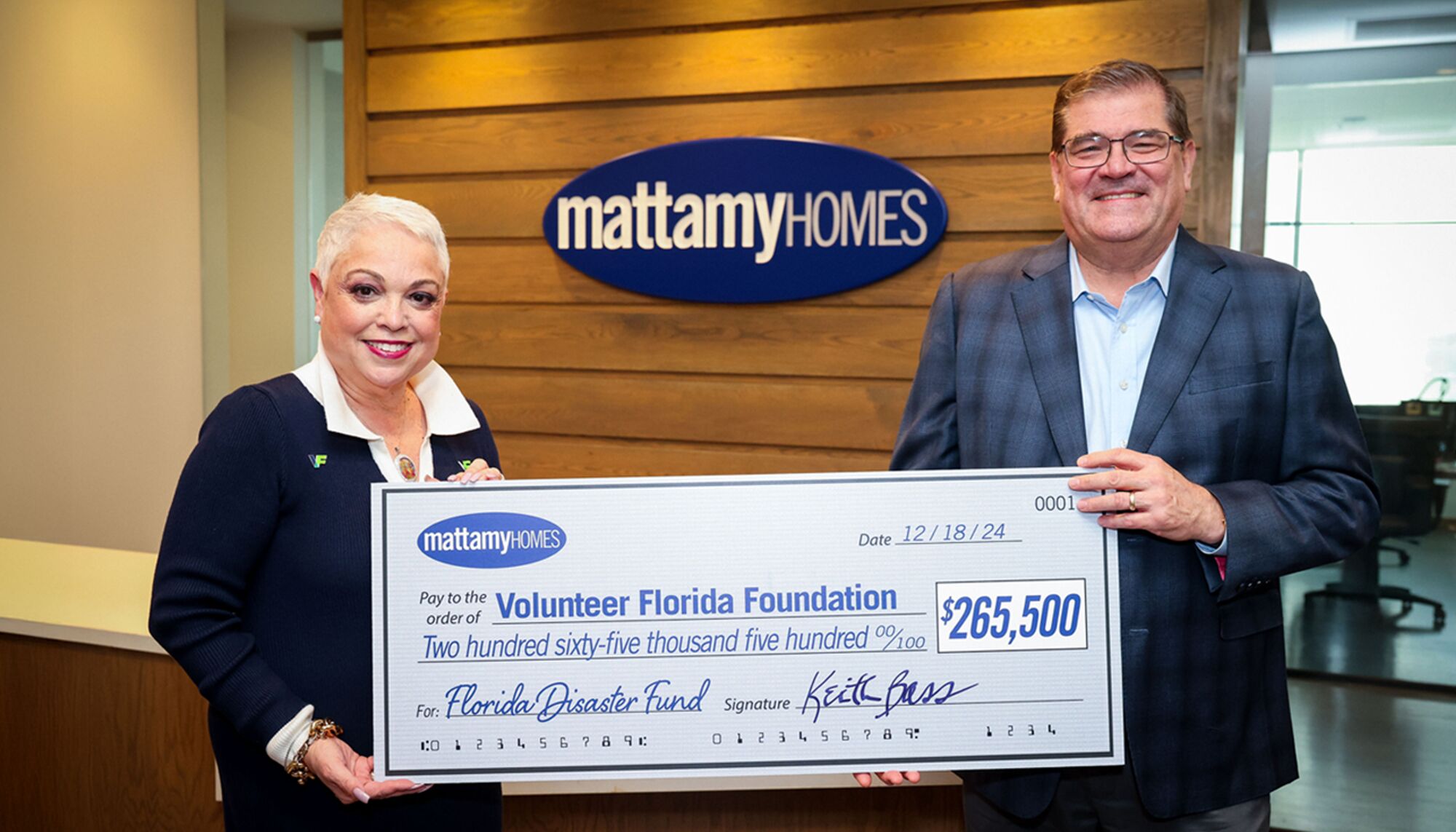 A man and a woman stand in front of a Mattamy Homes logo holding a cheque for $265,500