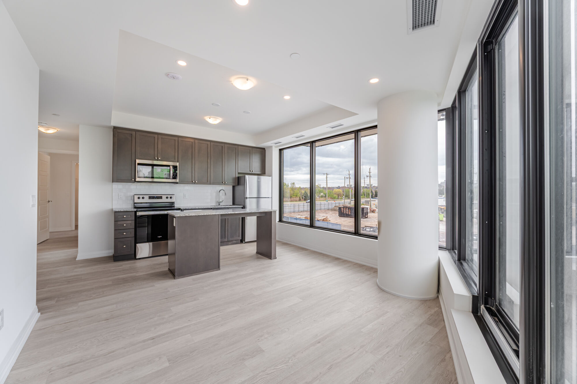 Condo kitchen with dark cabinetry, stainless steel appliances, kitchen island and granite countertops.