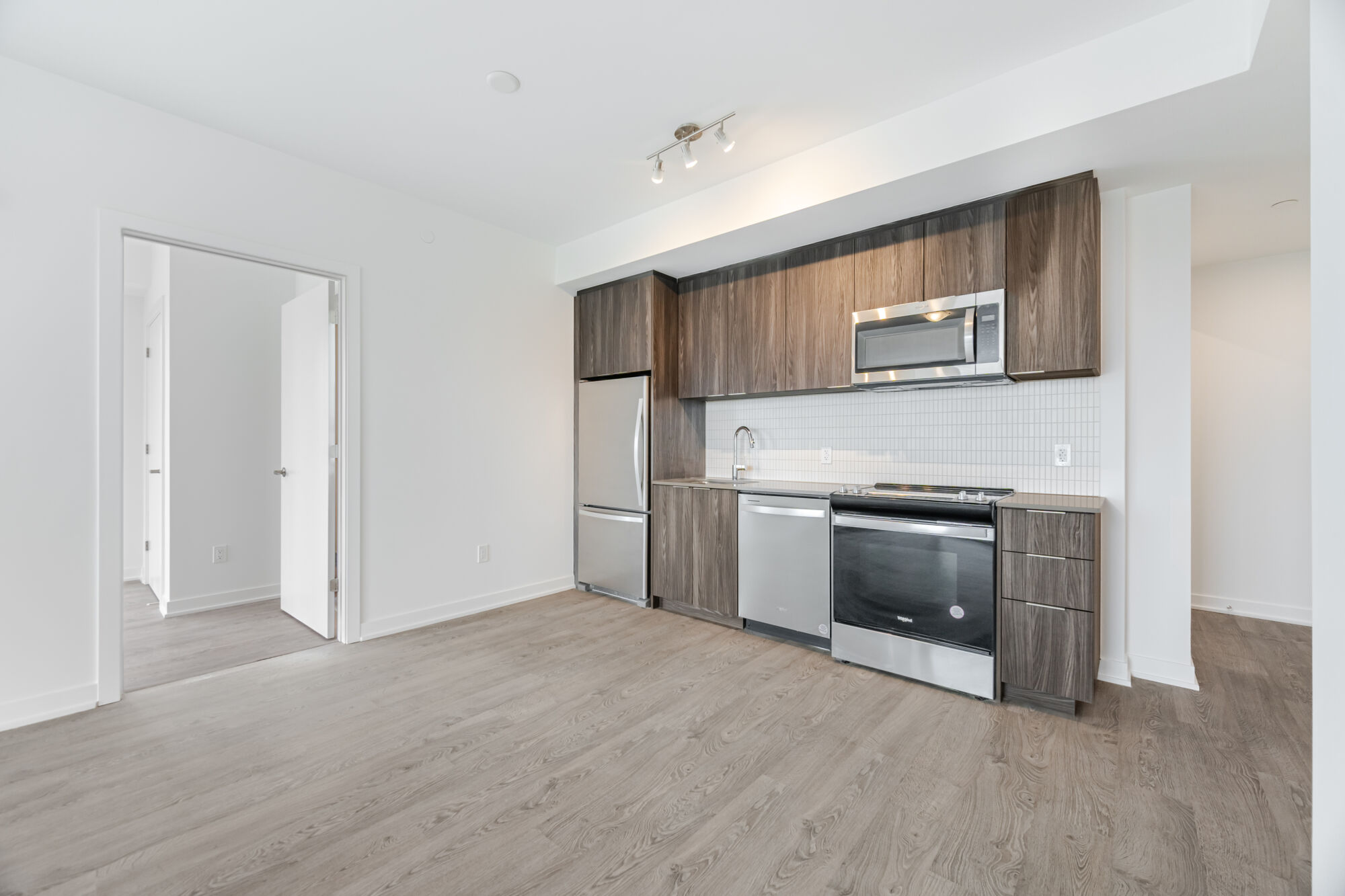 Condo kitchen with dark cabinetry, stainless steel appliances and quartz countertops.