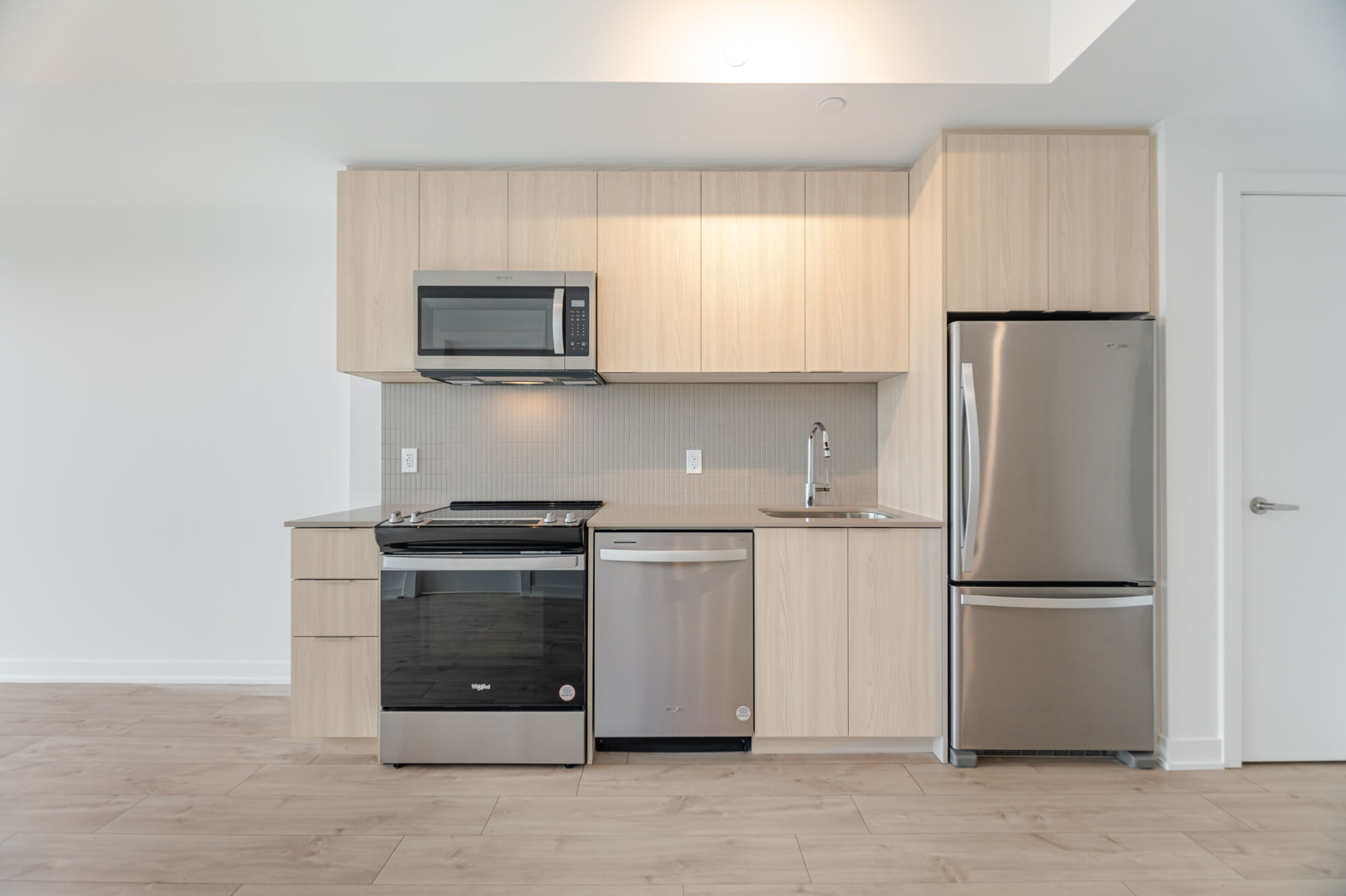 Condo kitchen with light cabinetry, stainless steel appliances and quartz countertops.
