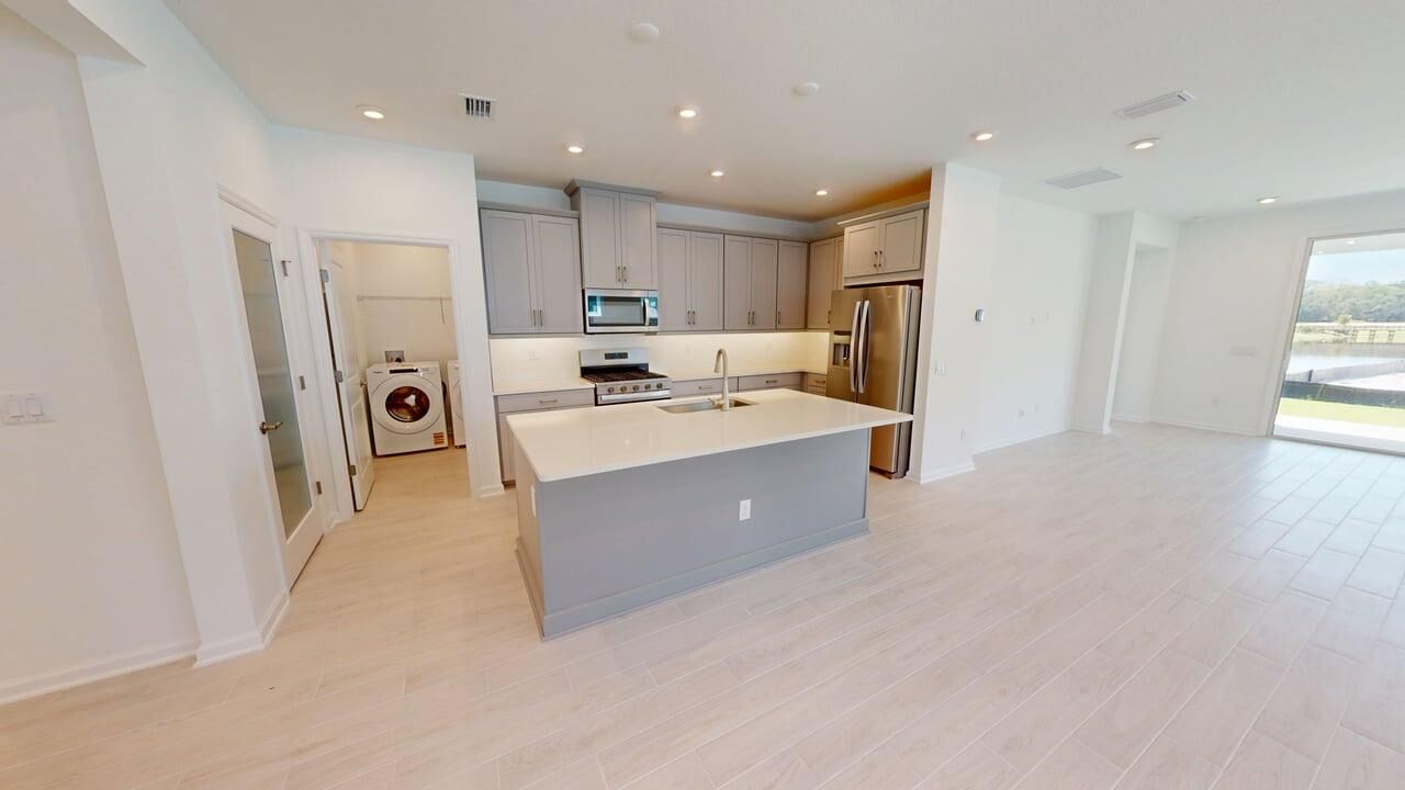 L-Shaped Kitchen with range, refrigerator, white cabinets, wood flooring and door