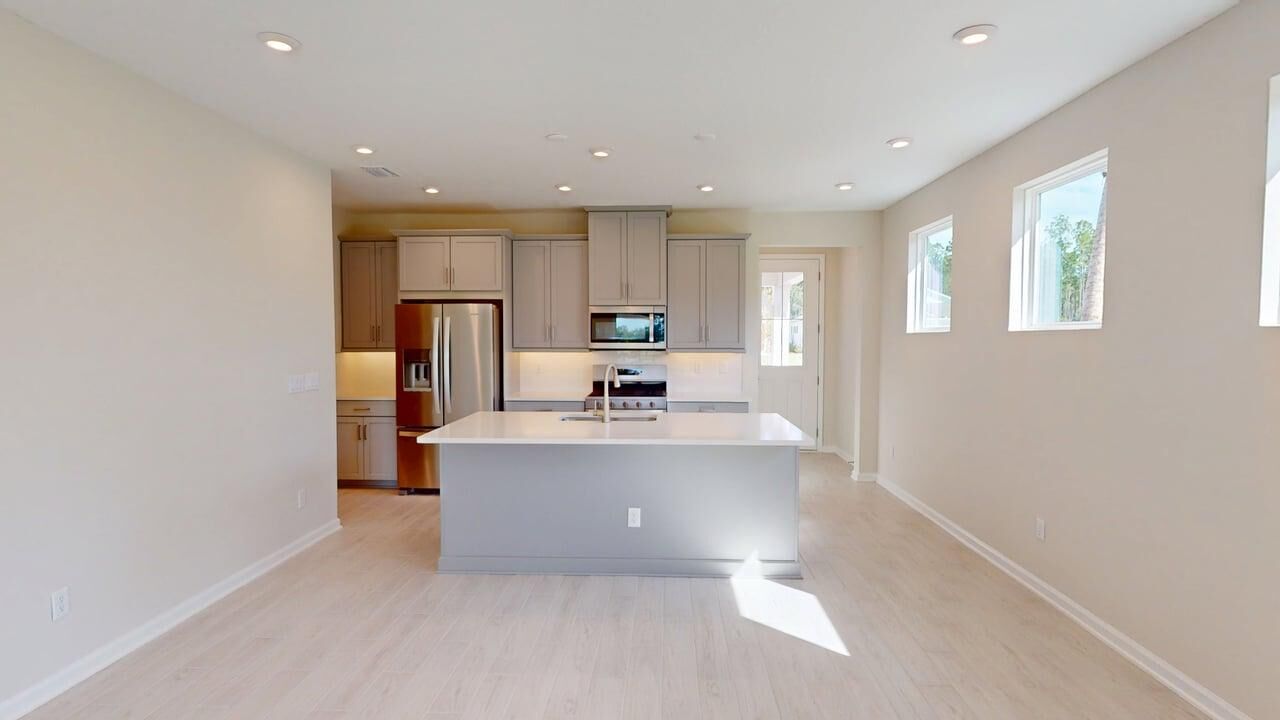Single-Wall Kitchen with window, refrigerator, door, white cabinets and wood flooring