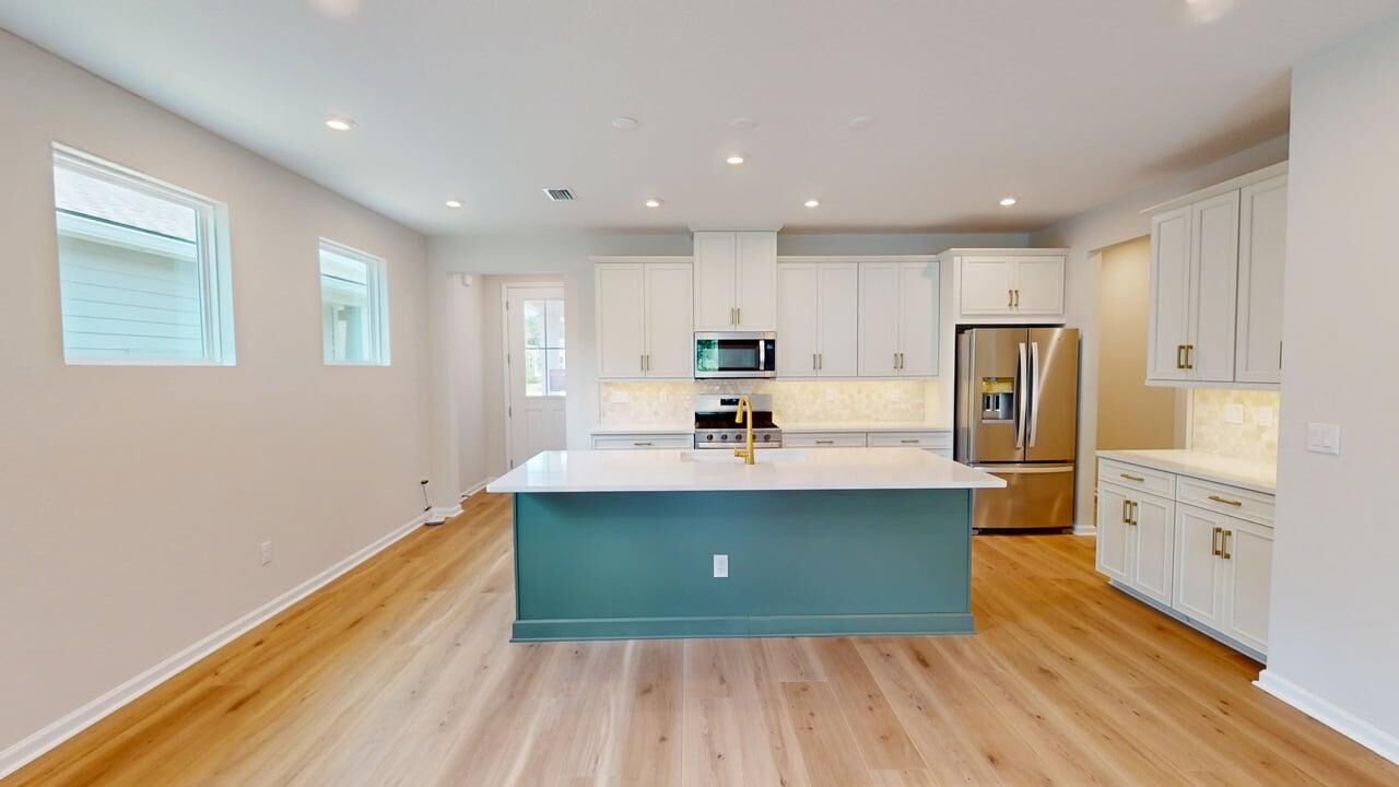 L-Shaped Kitchen with window, white cabinets, refrigerator, door and wood flooring