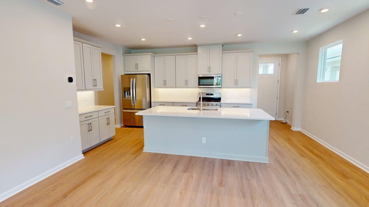 L-Shaped Kitchen with window, refrigerator, white cabinets, door, wood flooring and range