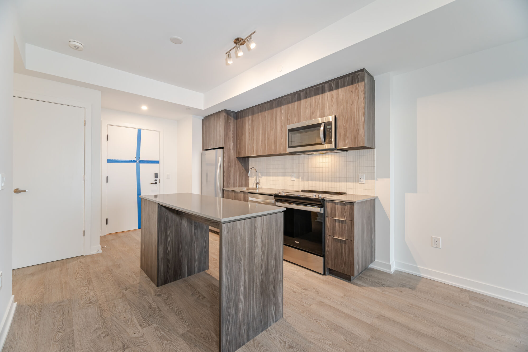 Condo kitchen with dark cabinetry, stainless steel appliances, kitchen island and quartz countertops.