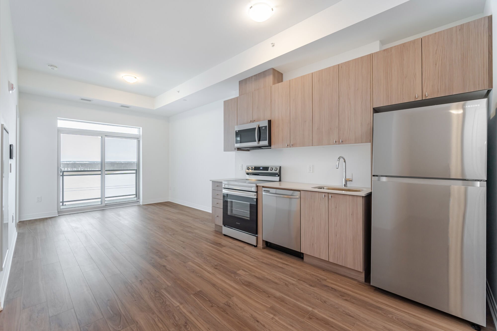 Condo kitchen with light cabinetry, stainless steel appliances and quartz countertops.