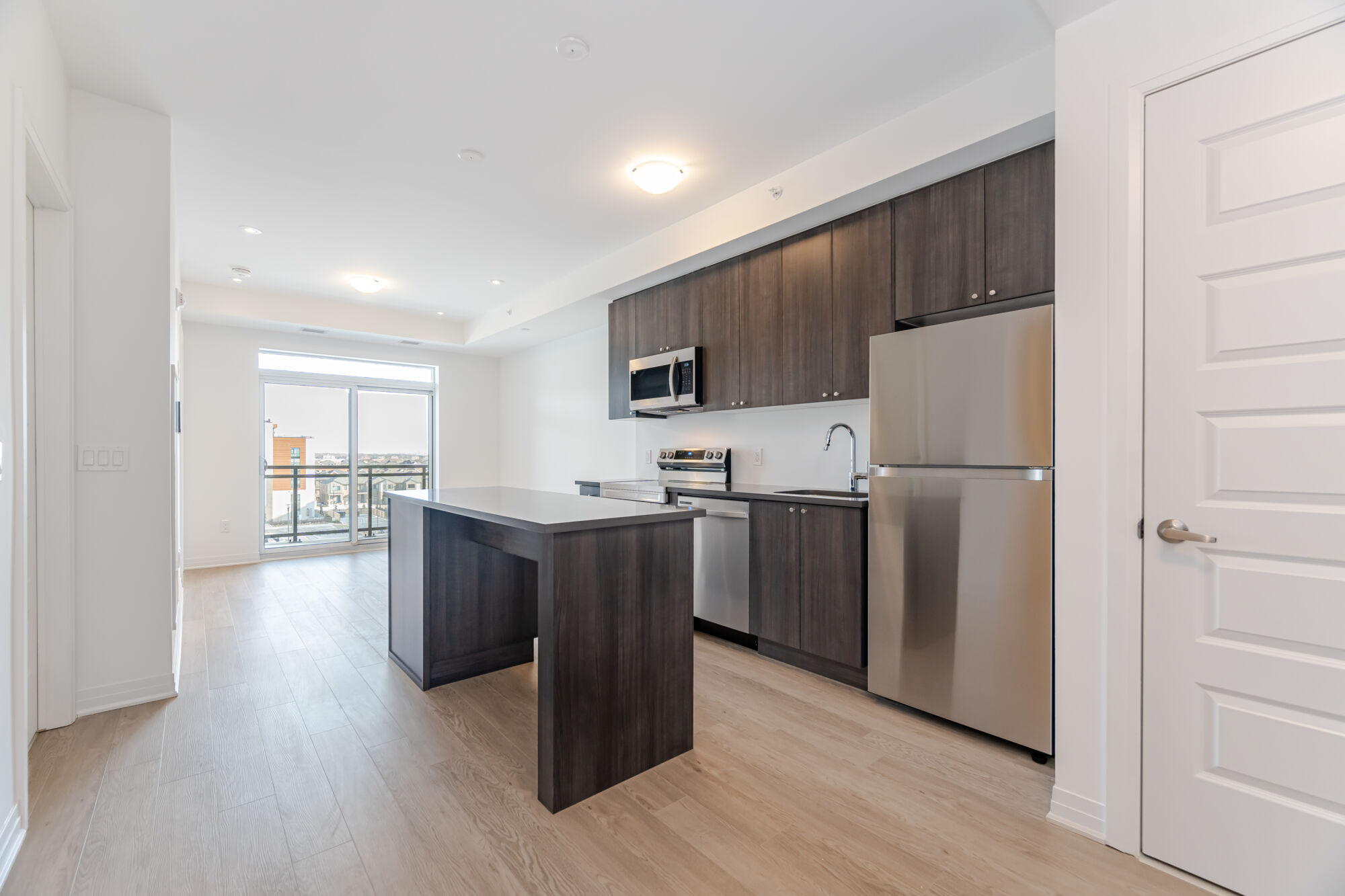 Condo kitchen with dark cabinetry, stainless steel appliances, kitchen island and quartz countertops.