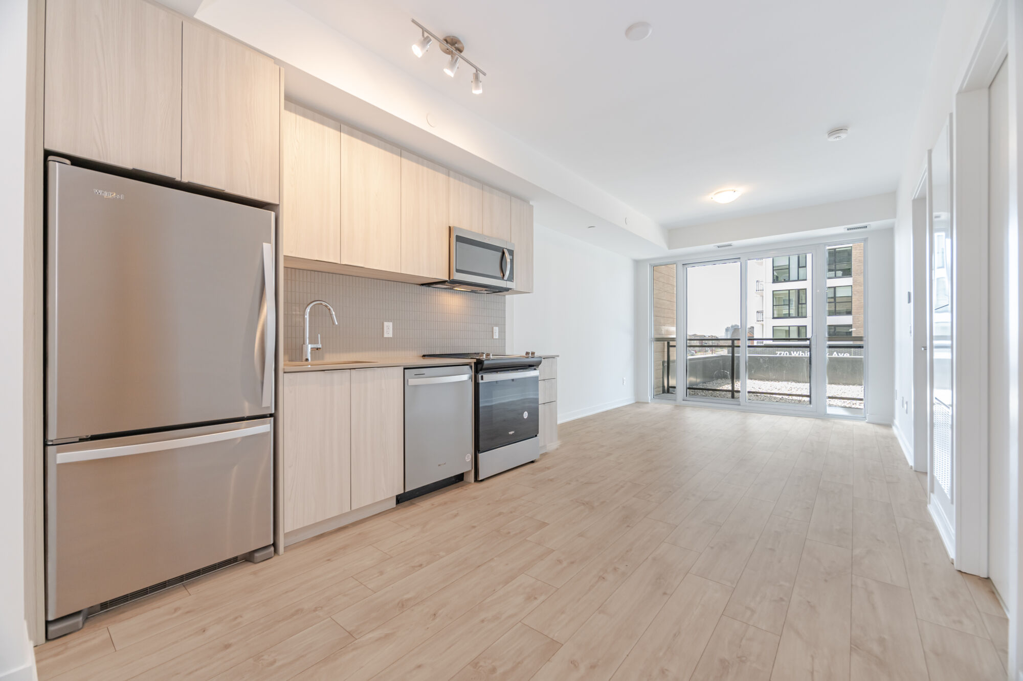 Condo kitchen with light cabinetry, stainless steel appliances and quartz countertops.