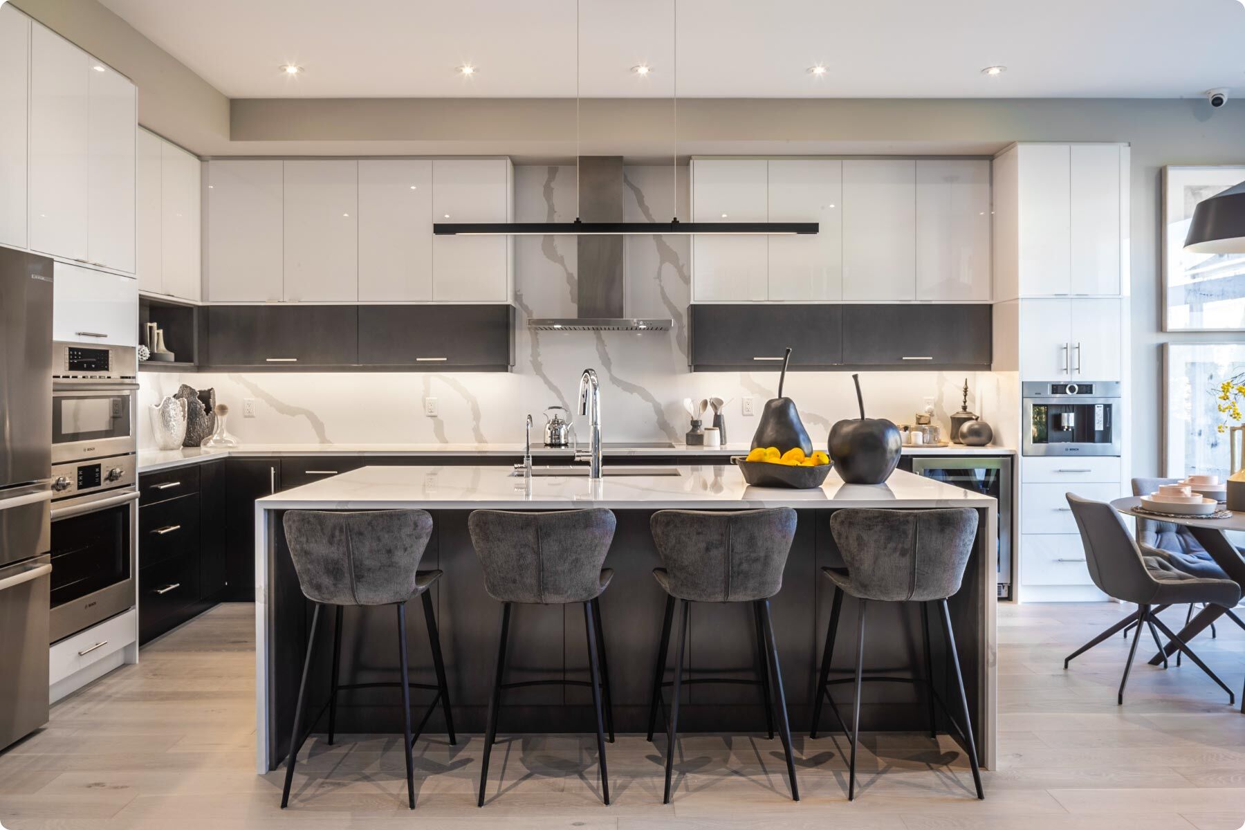 Kitchen with white upper cabinets and marble backsplash with a draped kitchen island and 4 barstools. 