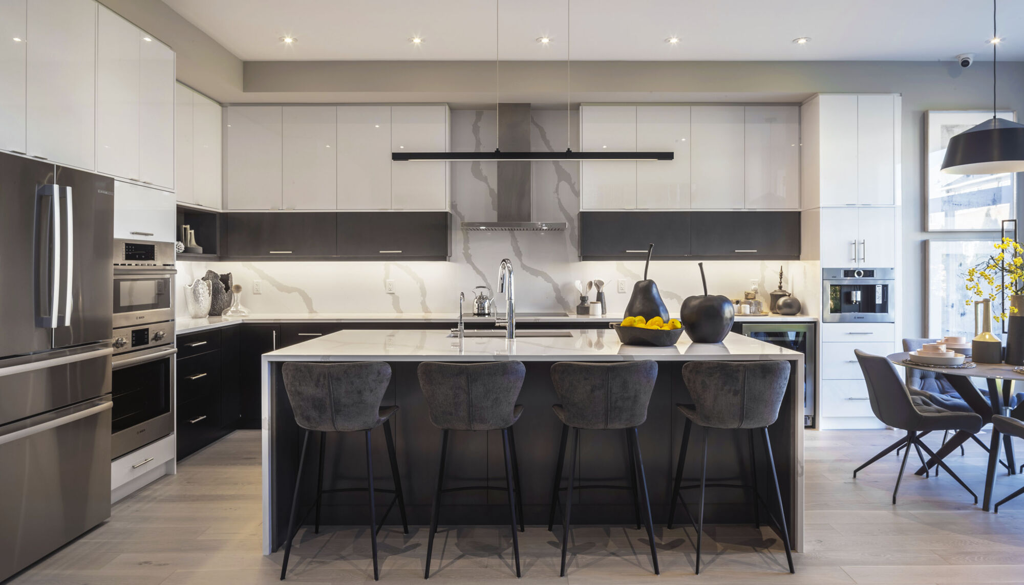 Kitchen with marble cabinets and a large marble island draped over the sides with grey chairs. 