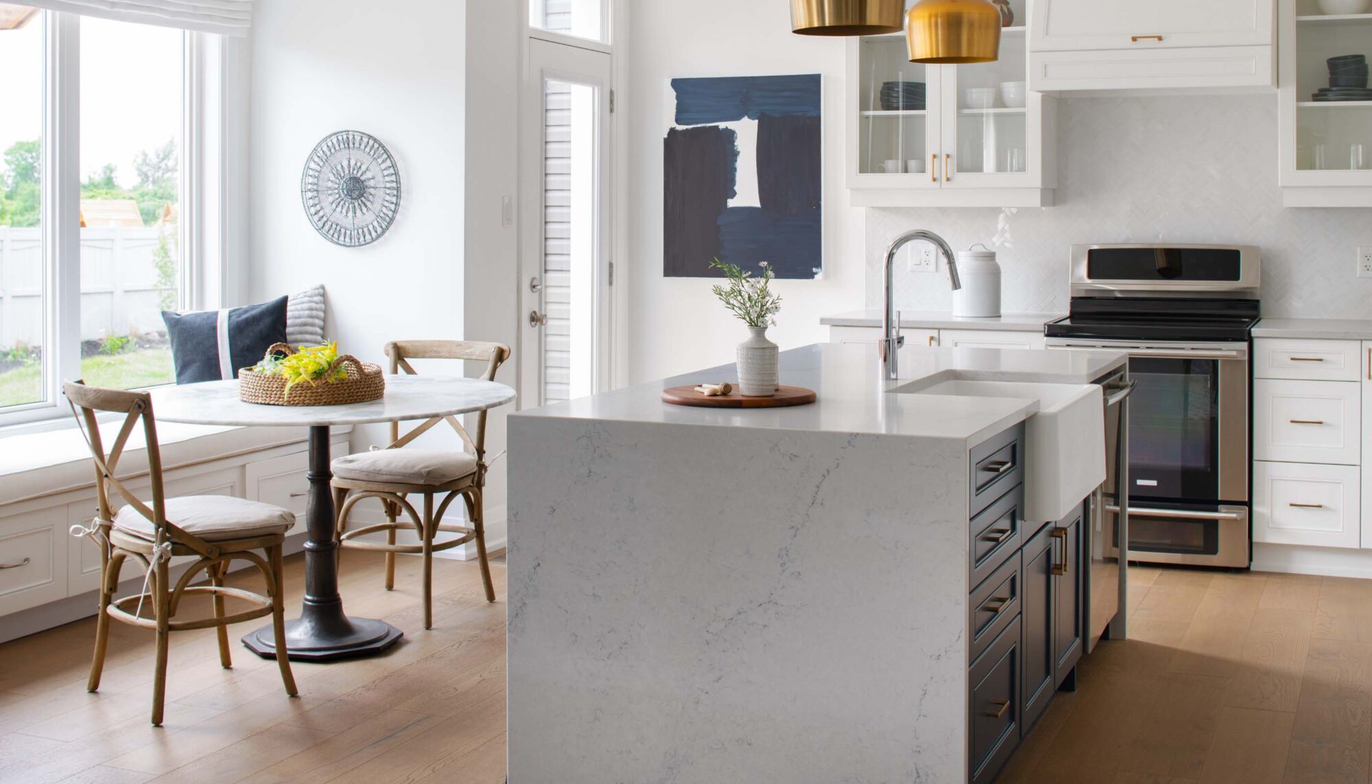 Kitchen and dining area with a white marble island, circular dining table, and white cabinets.