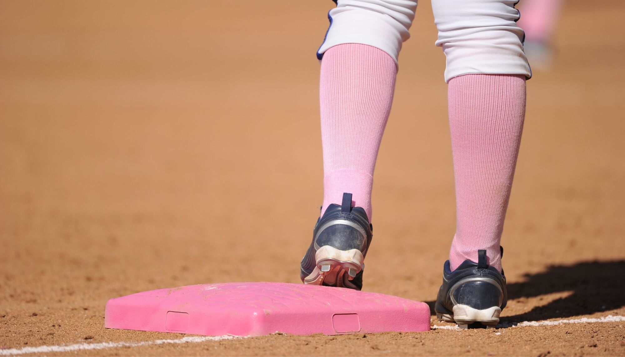 Person with pink socks standing on pink slo pitch plate