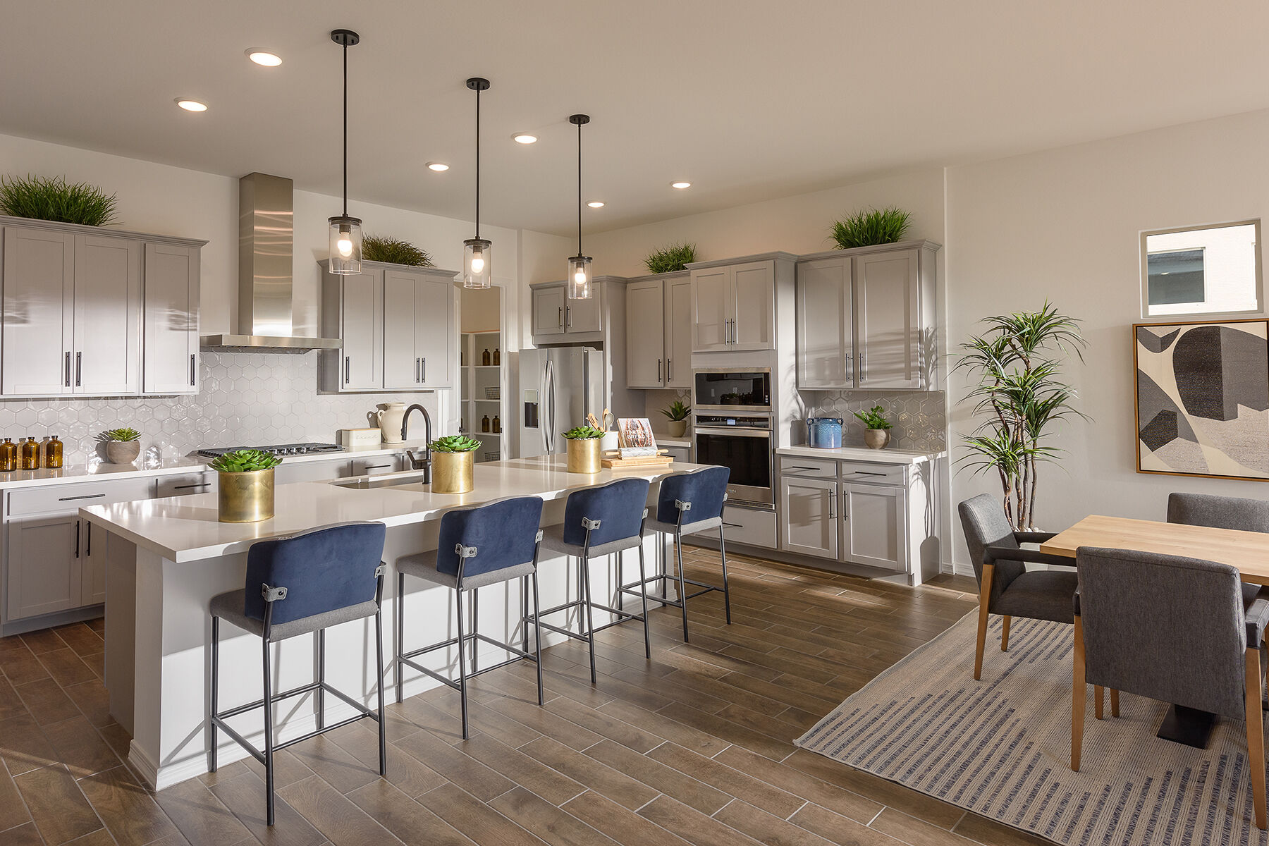 L-Shaped Kitchen with rug, oven, pendant light, refrigerator, painting, white cabinets, raised panel cabinets and wood flooring