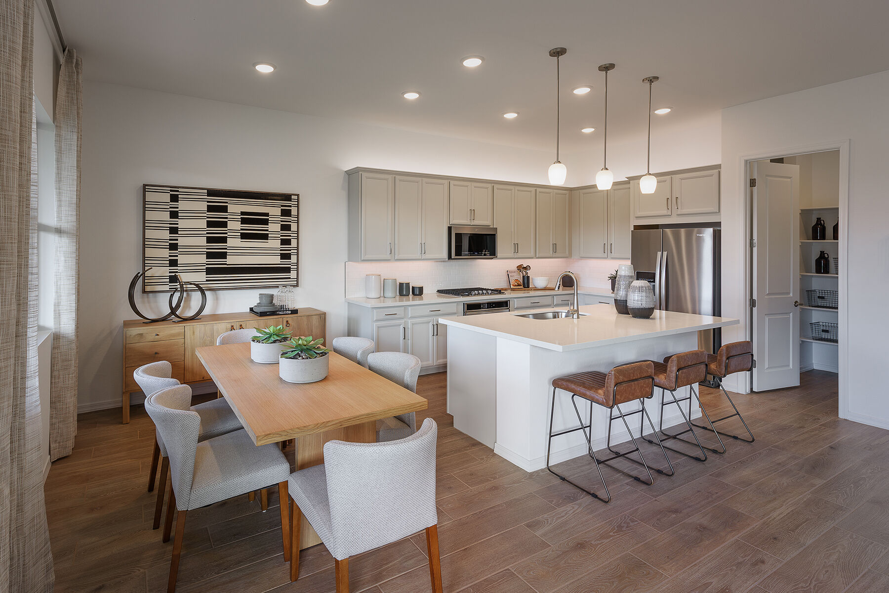 L-Shaped Kitchen with pendant light, refrigerator, door, curtains, mirror, range, wood flooring and white cabinets