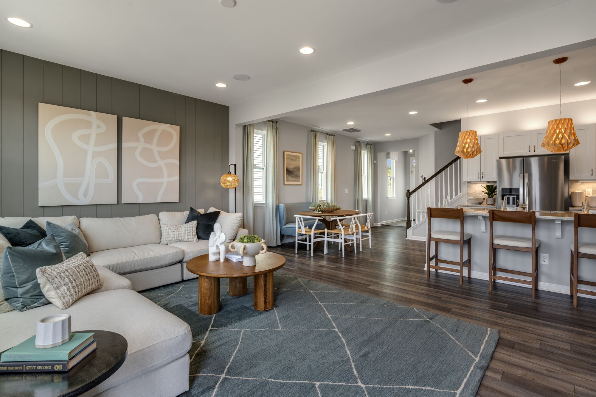 Greatroom with pendant light, painting, refrigerator, curtains, window, rug, white cabinets and wood flooring