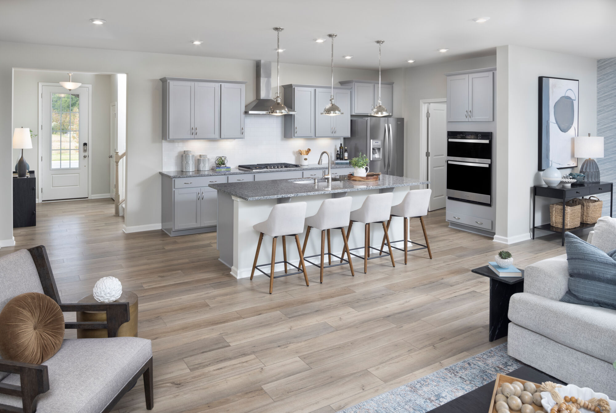  Greatroom with door, pendant light, range, refrigerator, painting, rug, wood flooring and white cabinets