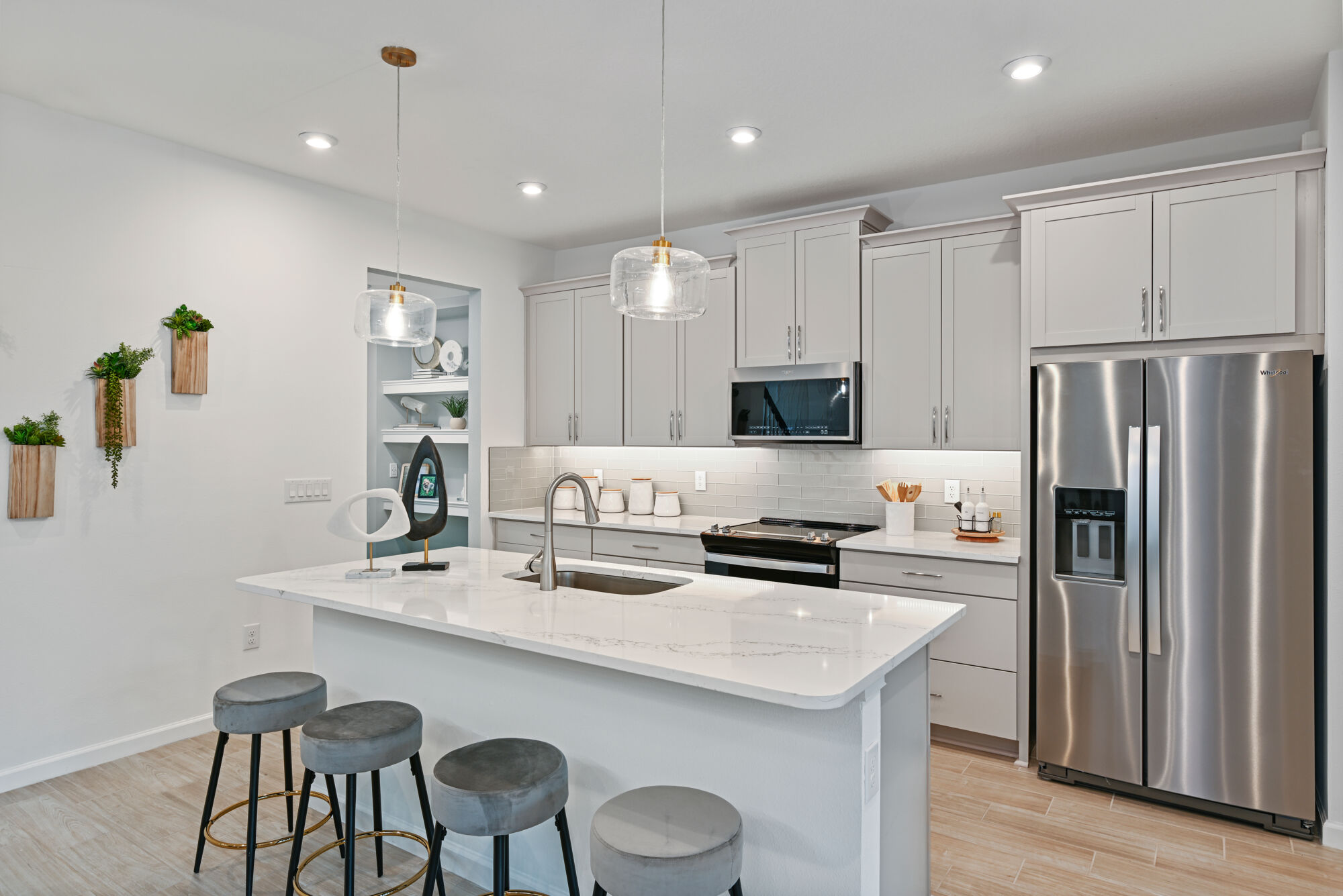 Single-Wall Kitchen with refrigerator, pendant light, range, white cabinets and wood flooring