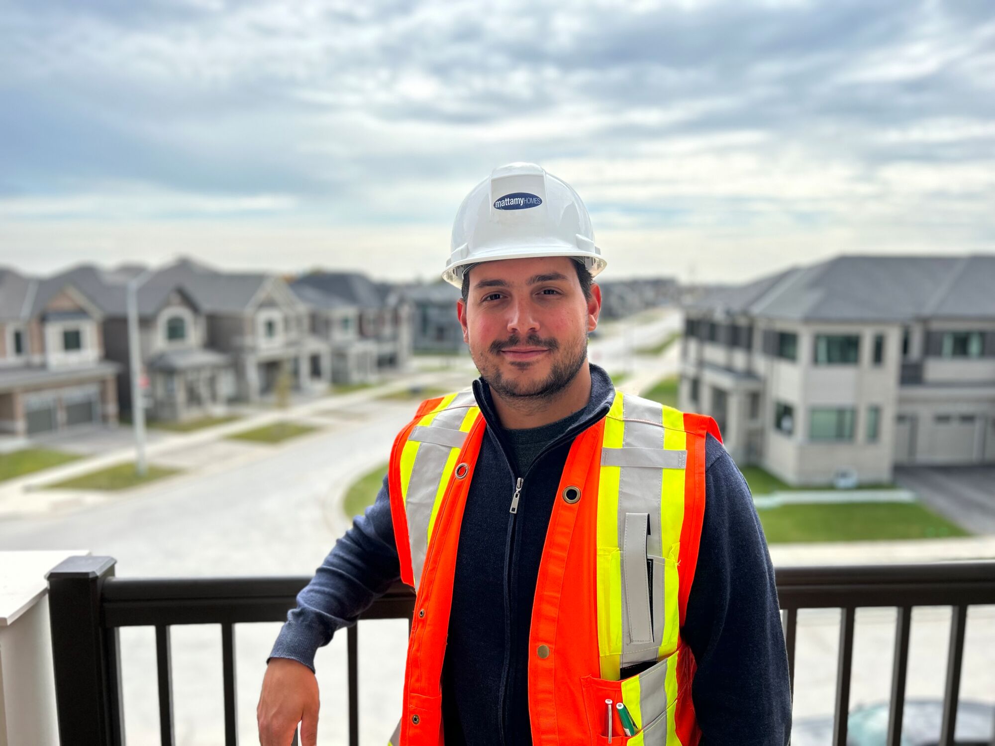 Mattamy employee wearing safety equipment standing outside on apartment balcony