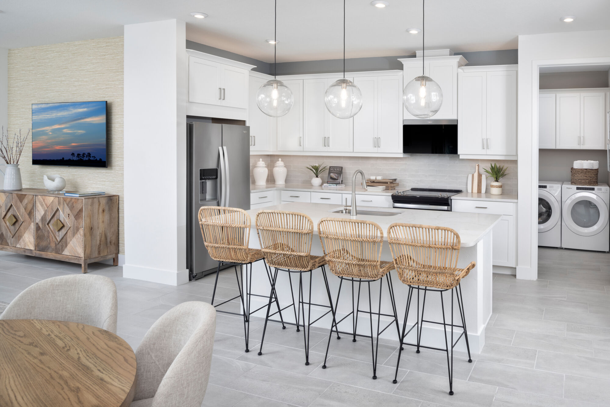 L-Shaped Kitchen with washer-dryer, refrigerator, pendant light, white cabinets and tile flooring