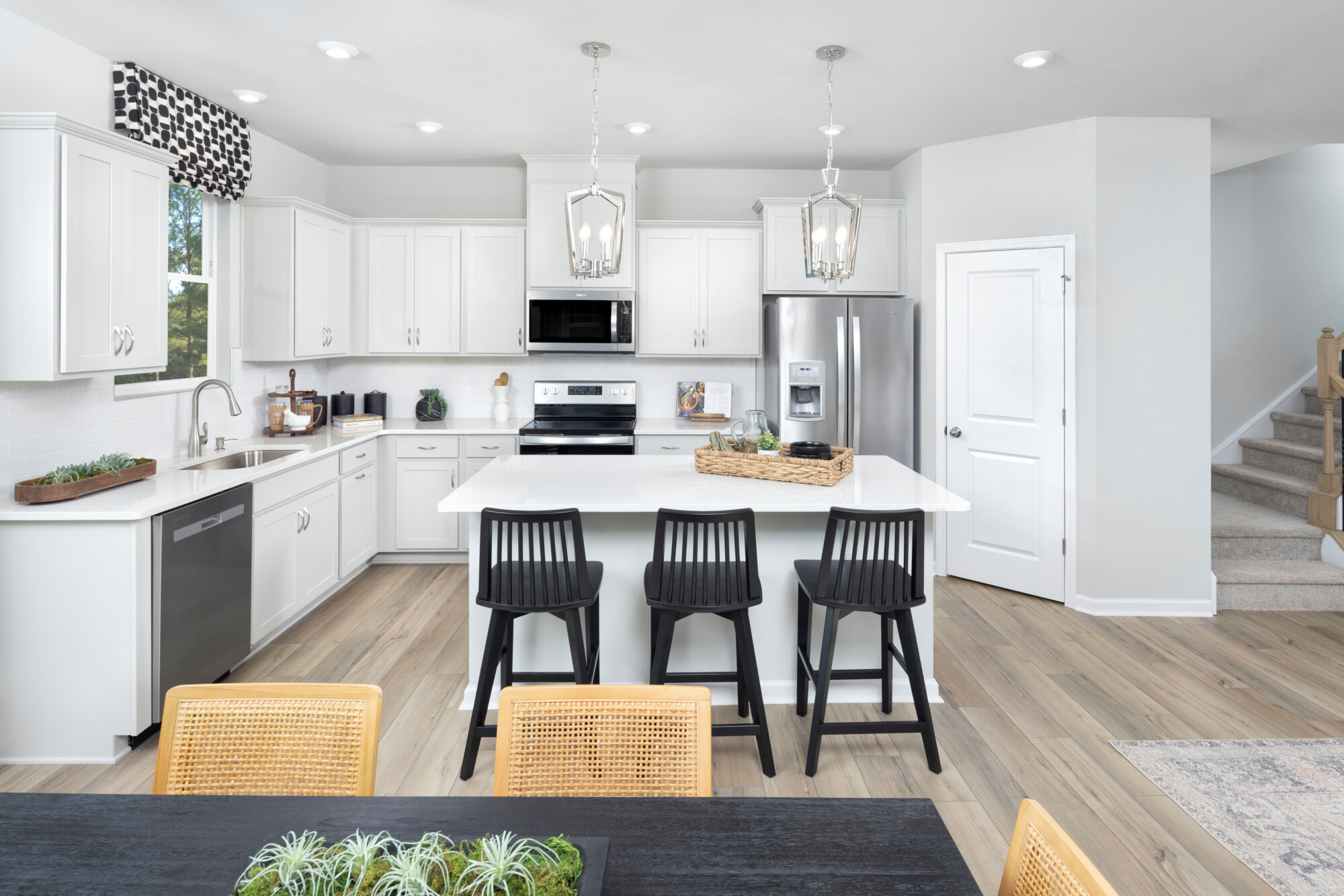  Kitchen with range, door, pendant light, refrigerator, rug, white cabinets and wood flooring