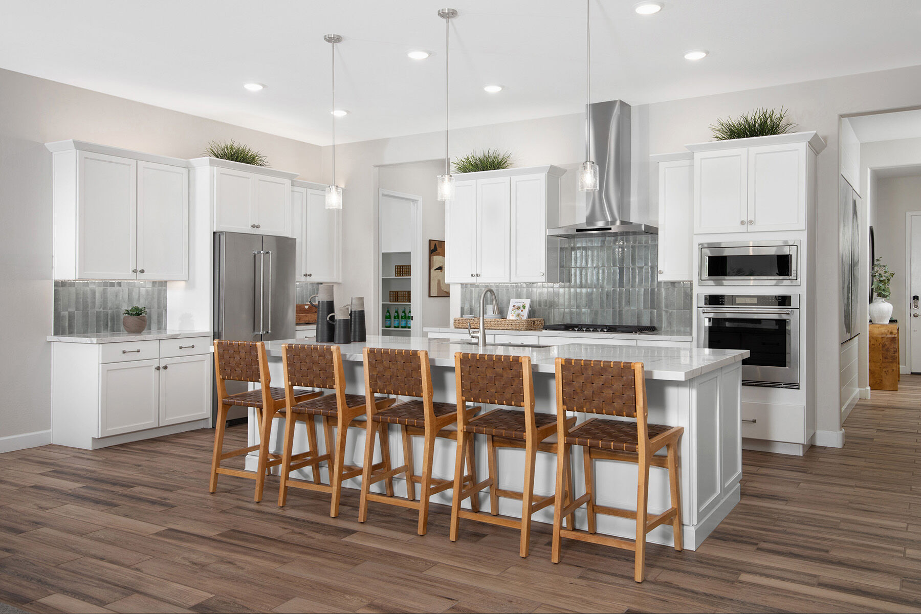 L-Shaped Kitchen with oven, pendant light, refrigerator, cooktop, painting, wood flooring and white cabinets