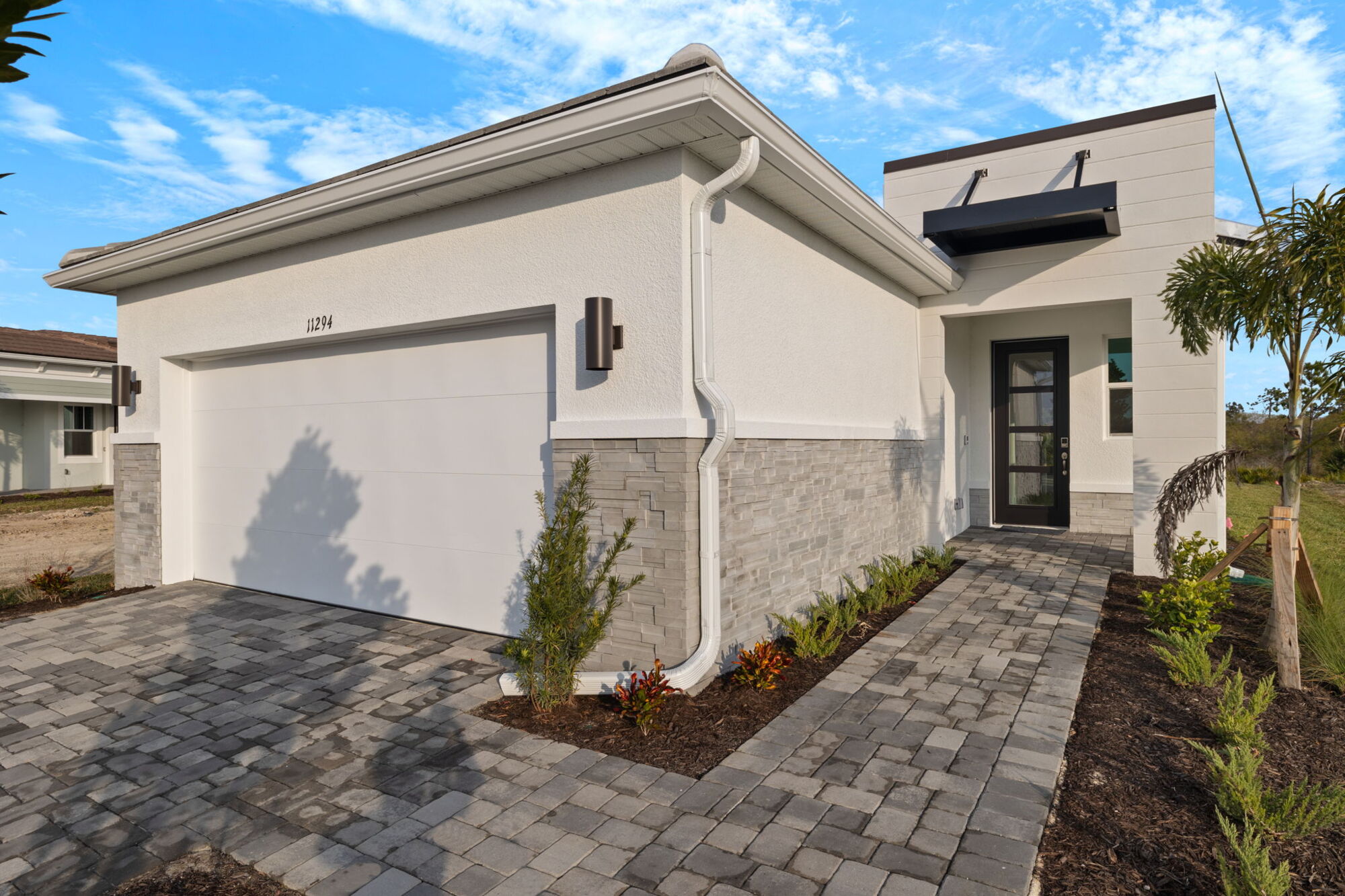 Single-family home, Sandstone, Transitional, contemporary, modern exterior, 2 bedrooms, 2 baths, powder room, laundry room, open concept, light shaker cabinets and quartz countertops throughout, vent hood with cook top, wall oven and microwave, stainless steel appliances, study, refrigerator, triple glass sliders to lanai, covered lanai with pavers, pantry, owner's bedroom with tray ceiling, shower with bench seat and glass wall, dual sink raised vanity, walk-in closet, floor outlet in great room, study with glass doors, crown molding
